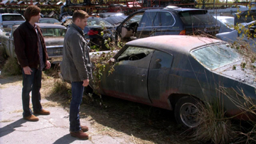 Sam and Dean pause to look at Bobby's old car.